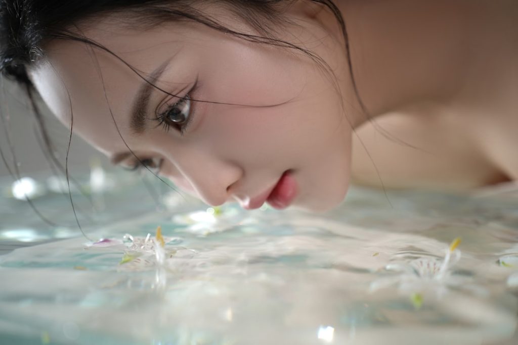 a-womans-face-looking-down-at-water-with-flowers-euzp1rfah8s